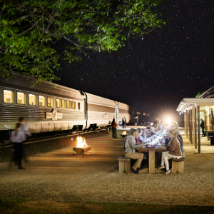 customers sitting at a long table with the Indian Pacific in the back