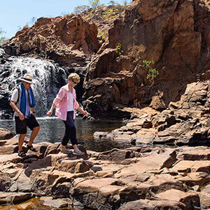 Two people exploring the red rocks of Nitmiluk