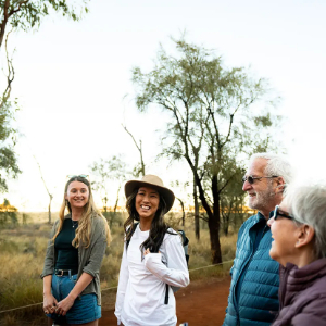 Group of people smiling and chatting in outback setting.