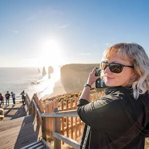 A woman taking a photo of the 12 Apostles