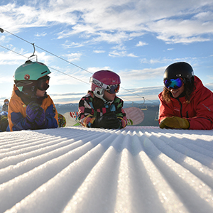 Two kids and an instructor laying in the snow