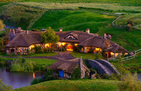 Hobbit house at dusk with the lights on