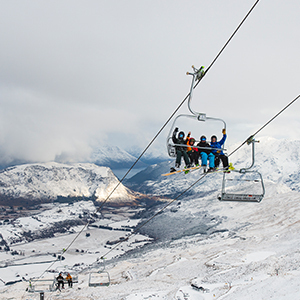 A chairlift on Coronet Peak flies through the clouds overlooking Queenstown