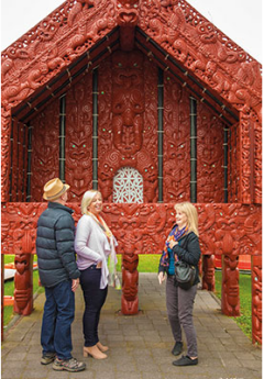 Group of travelers observing Maori carvings