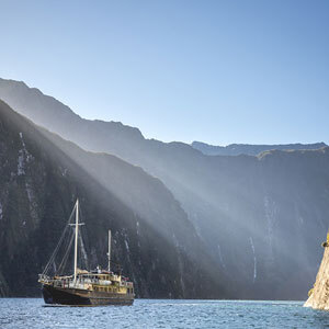 Image of a boat cruising spectacular Milford Sound on sunny day
